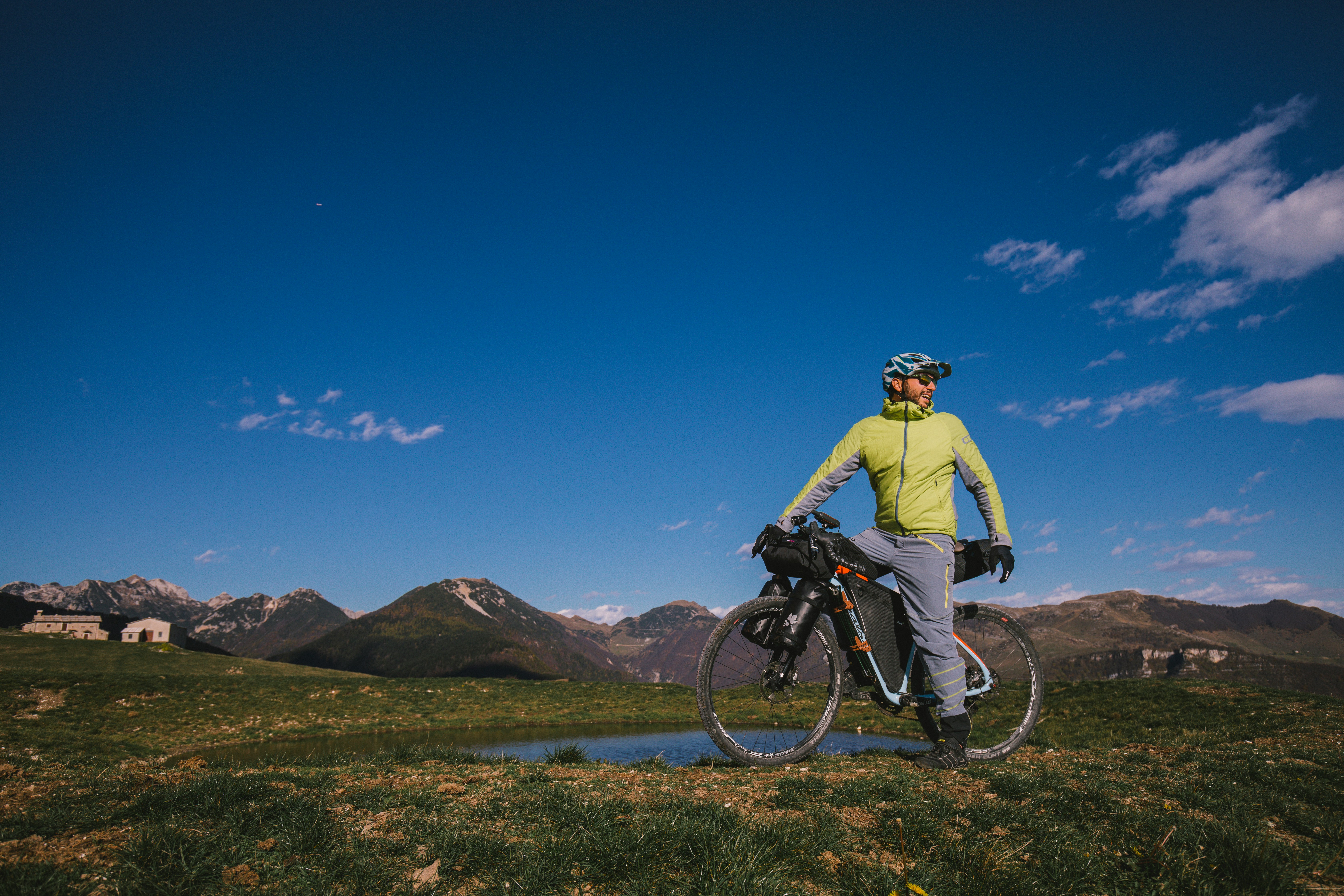 man in yellow jacket riding bicycle on dirt road during daytime